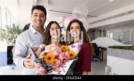 Des collègues heureux posant pour un portrait d'entreprise avec des fleurs et des ballons Banque D'Images