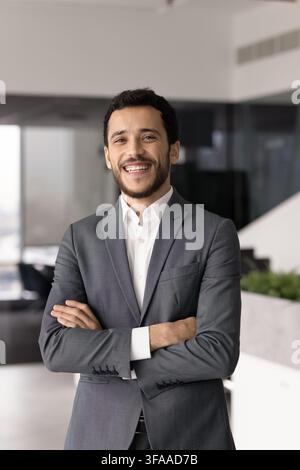 Homme d'affaires moyen-oriental confiant posant les bras croisés au bureau Banque D'Images