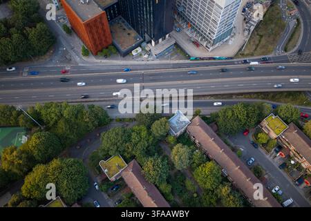 Image aérienne regardant directement vers le Mancunian Way avec le trafic et les habitations et développements adjacents pendant l'heure dorée à Manchester Banque D'Images
