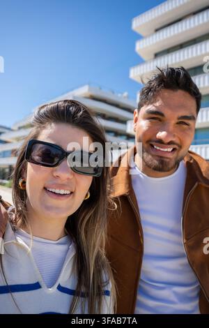 Jeune couple souriant prenant un selfie rapproché ensemble en plein air par une journée ensoleillée Banque D'Images