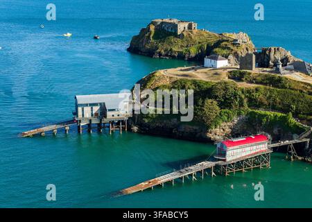 Anciennes et nouvelles stations de sauvetage avec de longues voies de lancement construites au-dessus de la mer turquoise en contrebas de Castle Hill et de l'île de St Catherine, Tenby, Pembrokeshire, Wa Banque D'Images