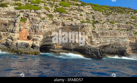 Falaises de calcaire côtières et grottes marines le long de la côte rocheuse de l'île de Vis, Croatie. Banque D'Images