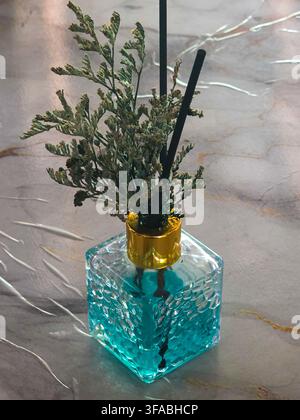 Un arrangement de fleurs séchées dans un vase en verre turquoise crée une décoration rustique sur une surface texturée Banque D'Images