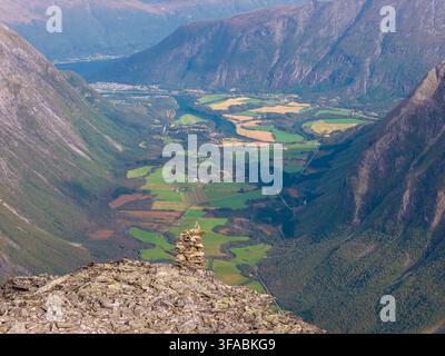 Vue aérienne du sommet Kongen avec un cairn en pierre au premier plan, surplombant la vallée verdoyante d'Isterdalen avec une rivière sinueuse et un champ Banque D'Images