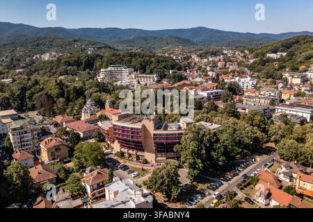 Panorama aérien par drone de Vrnjačka Banja, Serbie, photographié le 15 août 2026. L'image montre la ville thermale entourée de collines boisées et de verts pré Banque D'Images