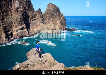 Femme reposant sur un promontoire rocheux surplombant le vaste océan Atlantique et les falaises dramatiques de Ponta de Sao Lourenco, Madère. Concept de courage, de découverte et de réalisation personnelle Banque D'Images