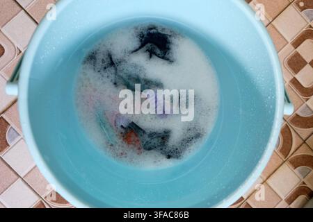 Vêtements trempant dans de l'eau de sopay à l'intérieur d'un seau en plastique pour le linge Banque D'Images