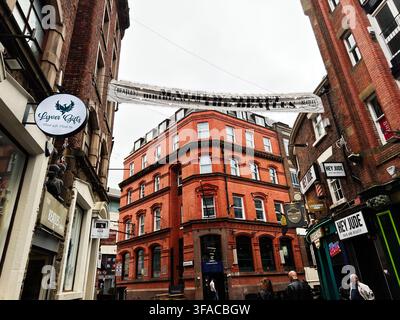 Liverpool, Royaume-Uni - 16 mai 2026 : Rue animée de Liverpool avec une signalisation emblématique des Beatles, une architecture en briques rouges, des devantures de magasins et des piétons. Banque D'Images