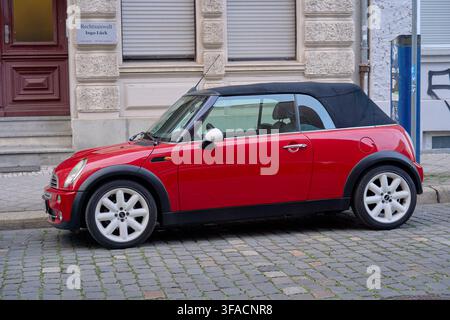 Mini Cooper Cabrio série R52, véhicule utilitaire rouge de petite taille au design britannique, garé sur une surface historique pavée à côté d'un cabinet d'avocat Banque D'Images