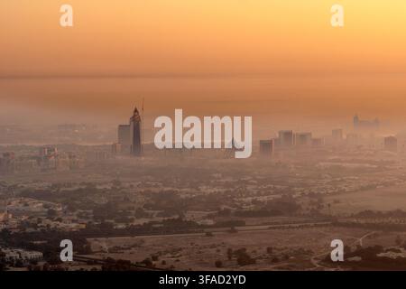 Vue aérienne de la skyline de Dubaï enveloppée dans une épaisse brume dorée du matin avec des gratte-ciel modernes s'élevant au-dessus du paysage désertique de Dubaï, Dubaï, Unité Banque D'Images