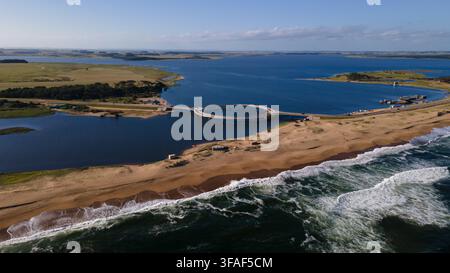 Vue aérienne de l'emblématique pont circulaire au-dessus de la Laguna Garzón, reliant les zones côtières de Maldonado, Uruguay. Capture l'eau bleue vibrante, le sable b Banque D'Images