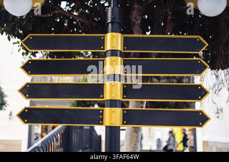Un panneau proéminent avec plusieurs flèches vierges est situé dans la zone urbaine. Sur fond de verdure luxuriante, indiquant diverses directions possibles pour Banque D'Images