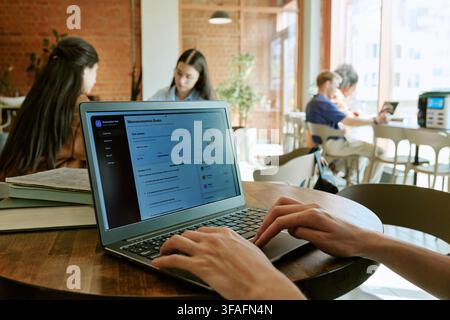 Différents étudiants étudiant sur un ordinateur portable dans la bibliothèque du campus universitaire Banque D'Images