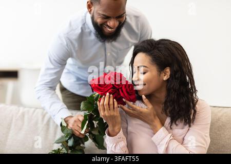 Jeune homme noir donnant des fleurs rouges à la femme Banque D'Images