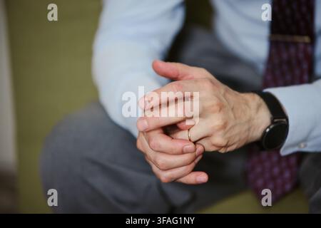 Close-up des mains jointes d'un homme d'affaires caucasien d'âge moyen touchant son alliance. Concept d'engagement matrimonial, d'anxiété ou de divorce, adapté aux services juridiques ou de conseil Banque D'Images