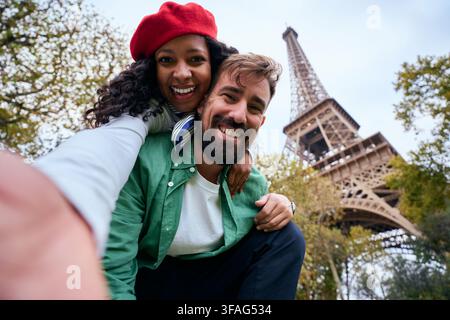 Couple heureux prenant un selfie près de la tour Eiffel à Paris. Banque D'Images