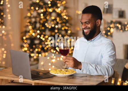 Un homme noir dînant sur un ordinateur portable lors d'une date virtuelle Banque D'Images