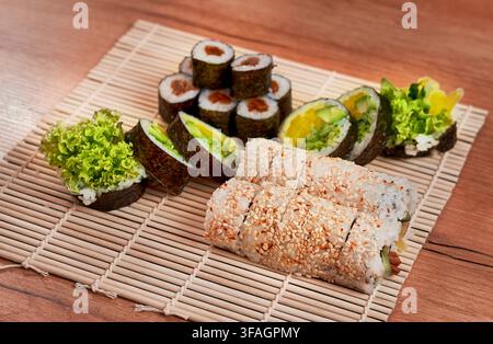 Assortiment de rouleaux de sushi végétariens frais servis sur un tapis à sushi traditionnel en bambou. Banque D'Images