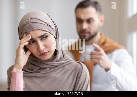 Un mari musulman agressif criait devant une femme déprimée debout à la maison Banque D'Images