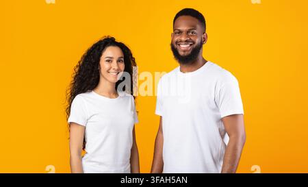 Couple multiethnique posant debout sur le fond jaune de studio, Panorama Banque D'Images