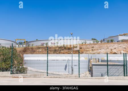 De grands réservoirs circulaires en béton sont visibles derrière une clôture métallique, faisant partie d'une usine de traitement de l'eau Banque D'Images