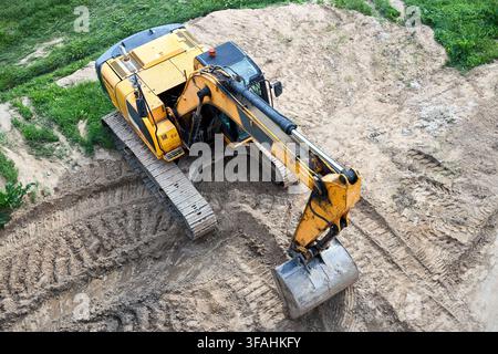 Excavatrice à chenilles jaune debout sur le sable sur le chantier de construction, vue aérienne, photographie aérienne, machines industrielles de construction travaillant avec le sol, godet Banque D'Images