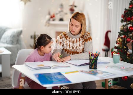 Mère et fille étudiant à la maison pendant les vacances d'hiver Banque D'Images