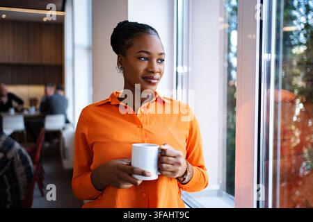Femme buvant du café et réfléchissant à l'avenir au bureau Banque D'Images