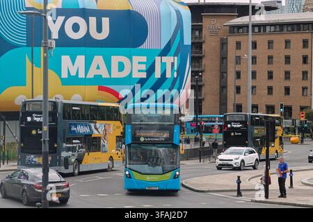 Des bus double-decker bleus d'Arriva passant devant les hôtels Delta et la fresque colorée du centre commercial St Johns à Liverpool, Royaume-Uni. Banque D'Images
