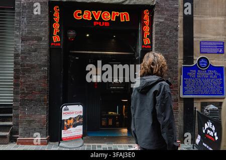 L’entrée et les panneaux néons emblématiques du The Cavern Pub sur Mathew Street, avec un piéton au premier plan à Liverpool, Royaume-Uni Banque D'Images