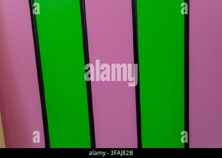 Texture en bois peinte de couleurs vives avec des rayures verticales alternées de vert éclatant et de rose séparées par de fines lignes noires dans une géométrie propre Banque D'Images