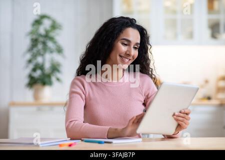Formation à distance. Bonne jeune femme étudier avec la tablette numérique dans la cuisine Banque D'Images