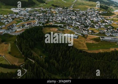 Vue aérienne du village avec son architecture alpine traditionnelle entourée de prairies verdoyantes et de forêts de pins denses à Fiss, Tyrol, Autriche. Banque D'Images