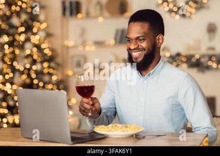 Afro homme ayant dîner pendant la date virtuelle sur ordinateur portable Banque D'Images
