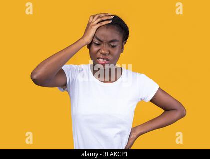 Femme afro-américaine souffrant de maux de tête graves, fond jaune Banque D'Images