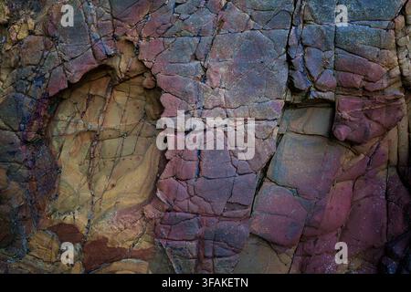 Grossissement d'une formation rocheuse magenta et violette avec des fissures naturelles et des motifs minéraux. Texture géologique abstraite vibrante Banque D'Images