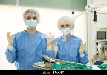 Dans la salle d'opération de la clinique vétérinaire, deux médecins expérimentés sont debout dans des combinaisons chirurgicales Banque D'Images