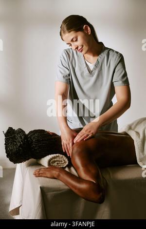 Massageuse femme massant le dos d'une femme noire dans un salon de spa Banque D'Images