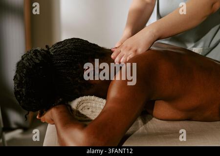 Femme noire recevant un massage professionnel du dos dans un spa Banque D'Images