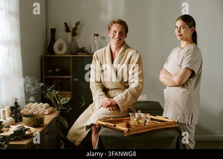 Portrait d'un homme et d'une masseuse souriant dans un salon de spa Banque D'Images