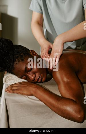 Femme noire recevant un massage relaxant du dos dans un salon de spa bien-être Banque D'Images