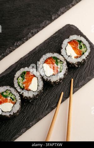 Rouleaux de sushi au saumon frais sur un plateau d'ardoise noire Banque D'Images