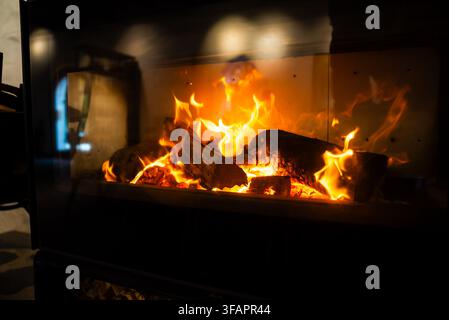 Les flammes brûlent vivement au-dessus des bûches dans une cheminée moderne d'intérieur Banque D'Images