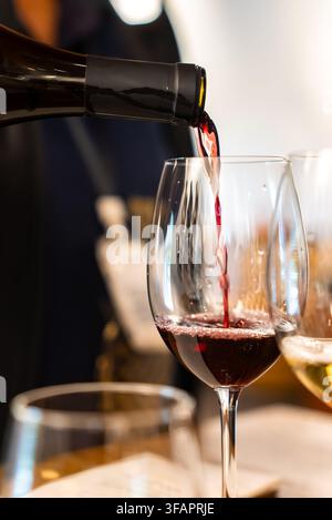 Du vin rouge est versé dans un gobelet en verre transparent lors d'une dégustation Banque D'Images