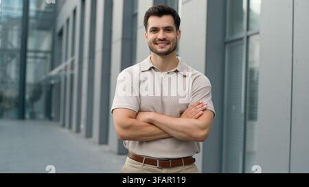 Homme d'affaires caucasien heureux souriant joyeusement, posant les bras croisés dans la ville, homme d'affaires, homme exécutif, sourire, bras croisés, regard confiant Banque D'Images