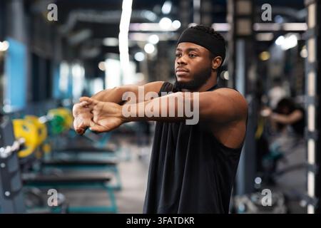 Homme noir sportif qui s'étire les mains dans la salle de sport Banque D'Images
