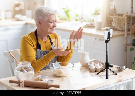 Femme âgée blogueuse de nourriture enregistrant sa cuisine sur smartphone Banque D'Images