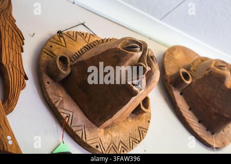 Des masques tribaux en bois sculpté sont accrochés à un mur blanc en Namibie Banque D'Images