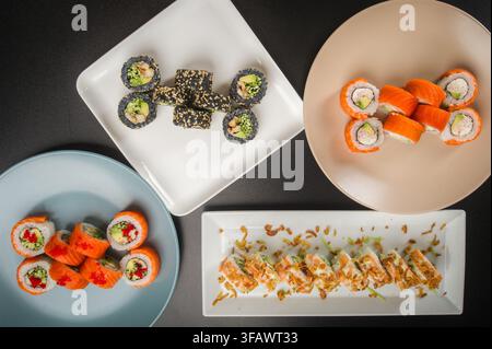 Assortiment de sushis japonais servis sur une longue assiette rectangulaire blanche avec fond sombre, photographie macro. Banque D'Images