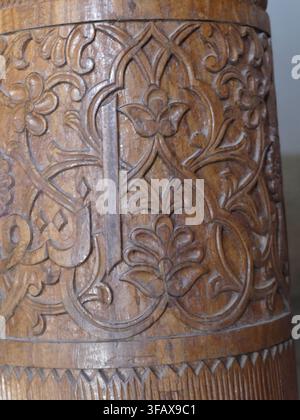 KHIVA, OUZBÉKISTAN - 14 SEPT 2024 - Colonne en bois sculptée à la main présentant un art islamique traditionnel avec des ornements floraux détaillés et une calligraphie el Banque D'Images
